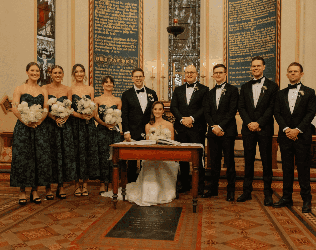 Brides ladies and grooms men stand next to newly wed couple