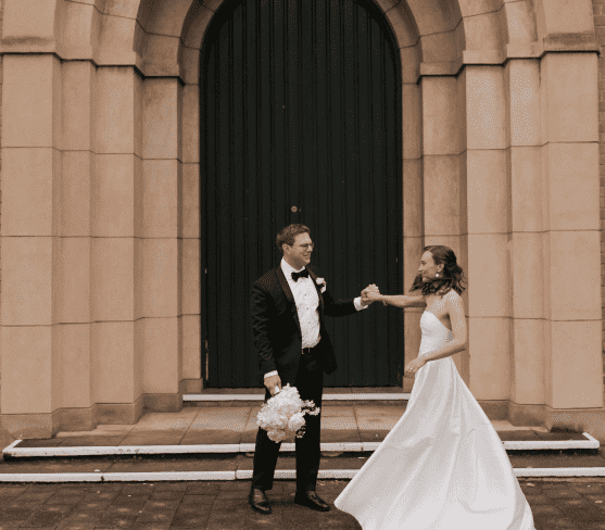 bride and groom outside church playfully holding hands